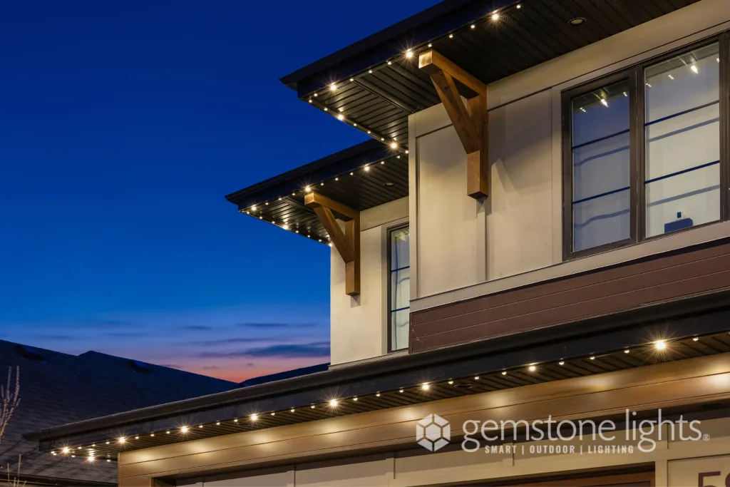 Twinkling lights adorn the eaves of a stylish modern home at dusk