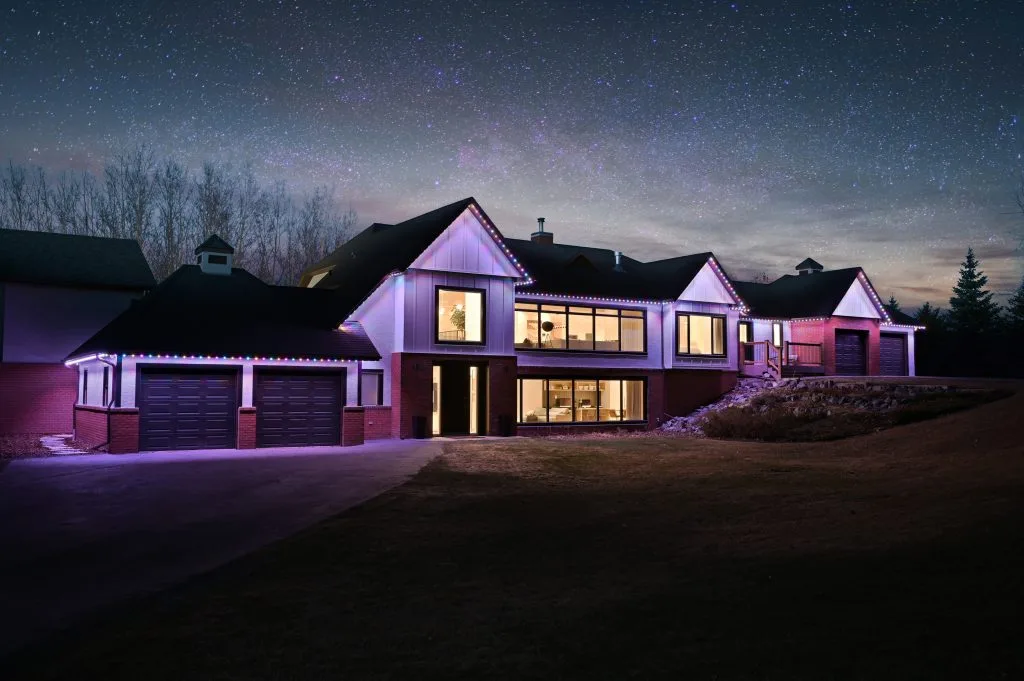 A modern house is illuminated under a starry night sky