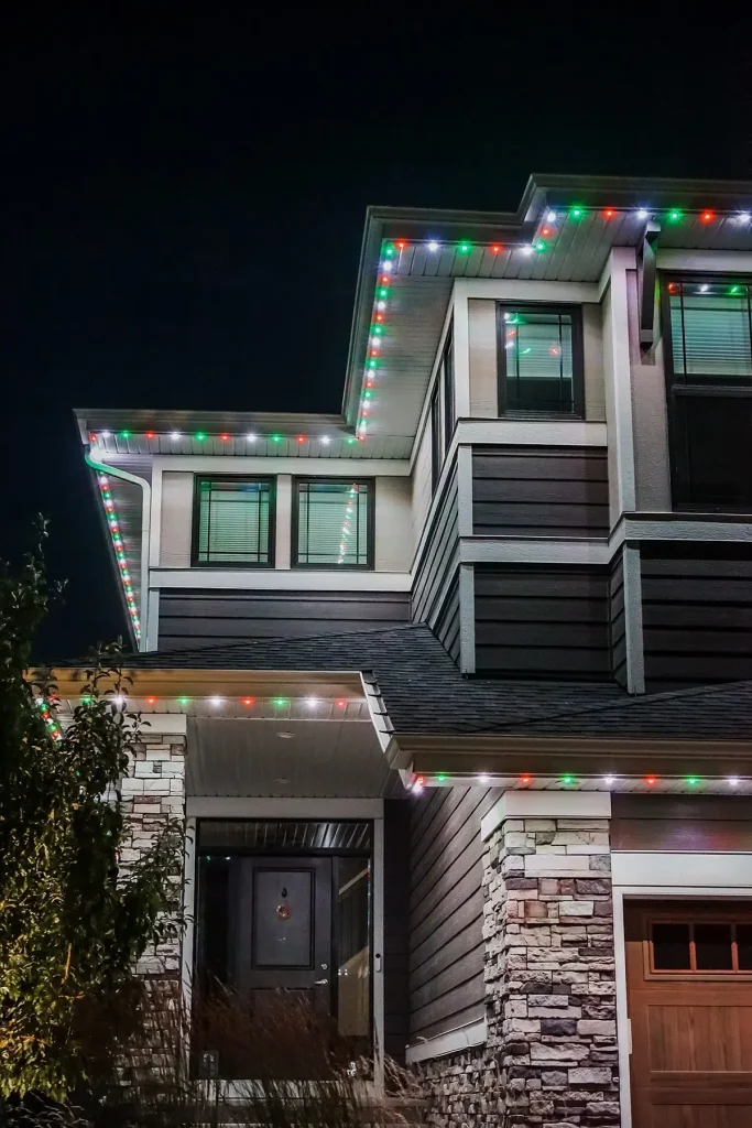 A house is illuminated with colorful holiday lights outlining its roof
