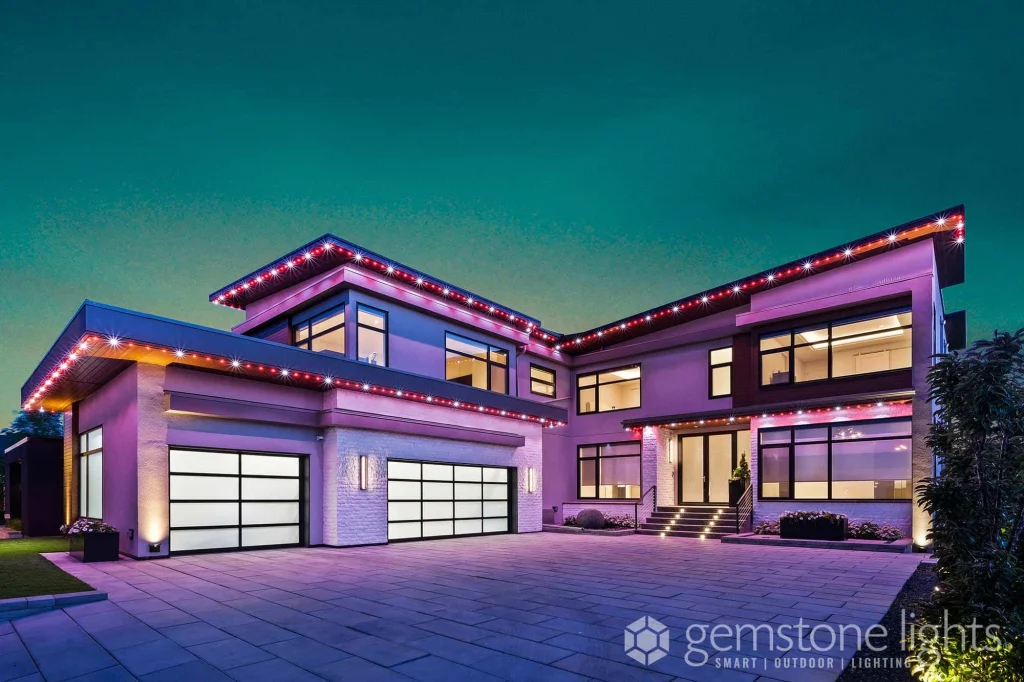 A modern house is illuminated with colorful lights against a twilight sky
