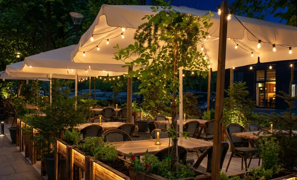 Warmly lit outdoor dining area adorned with greenery and cozy seating