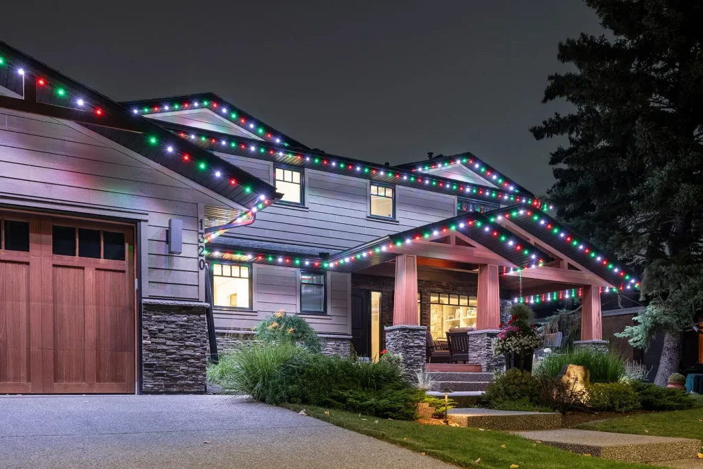 A house is illuminated with colorful holiday lights along the roofline